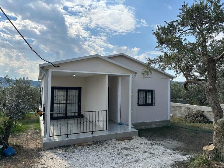 Beyaz cepheli, verandalı küçük prefabrik ev